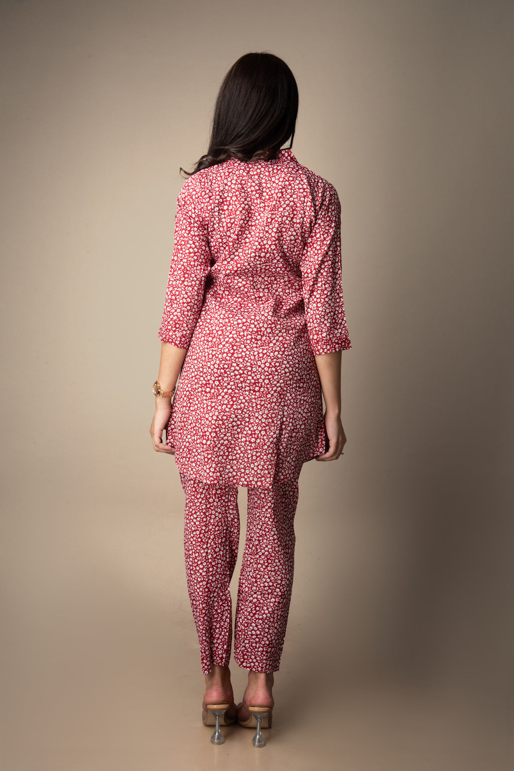 Woman wearing a red patterned outfit against a beige background
