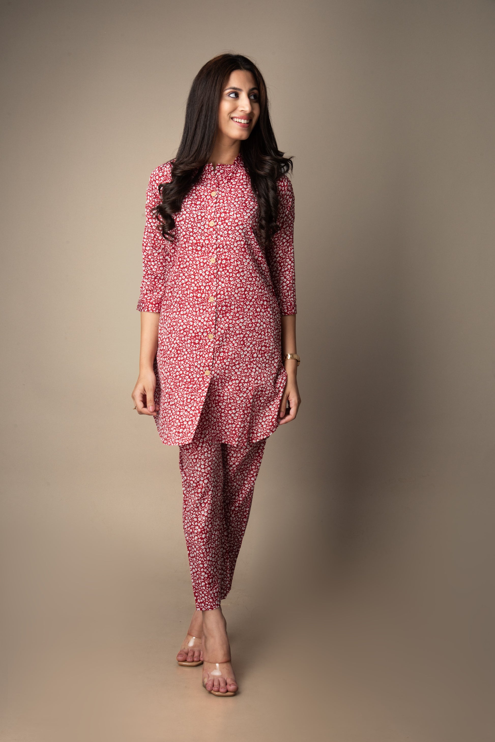 Woman wearing a pink floral outfit against a plain background