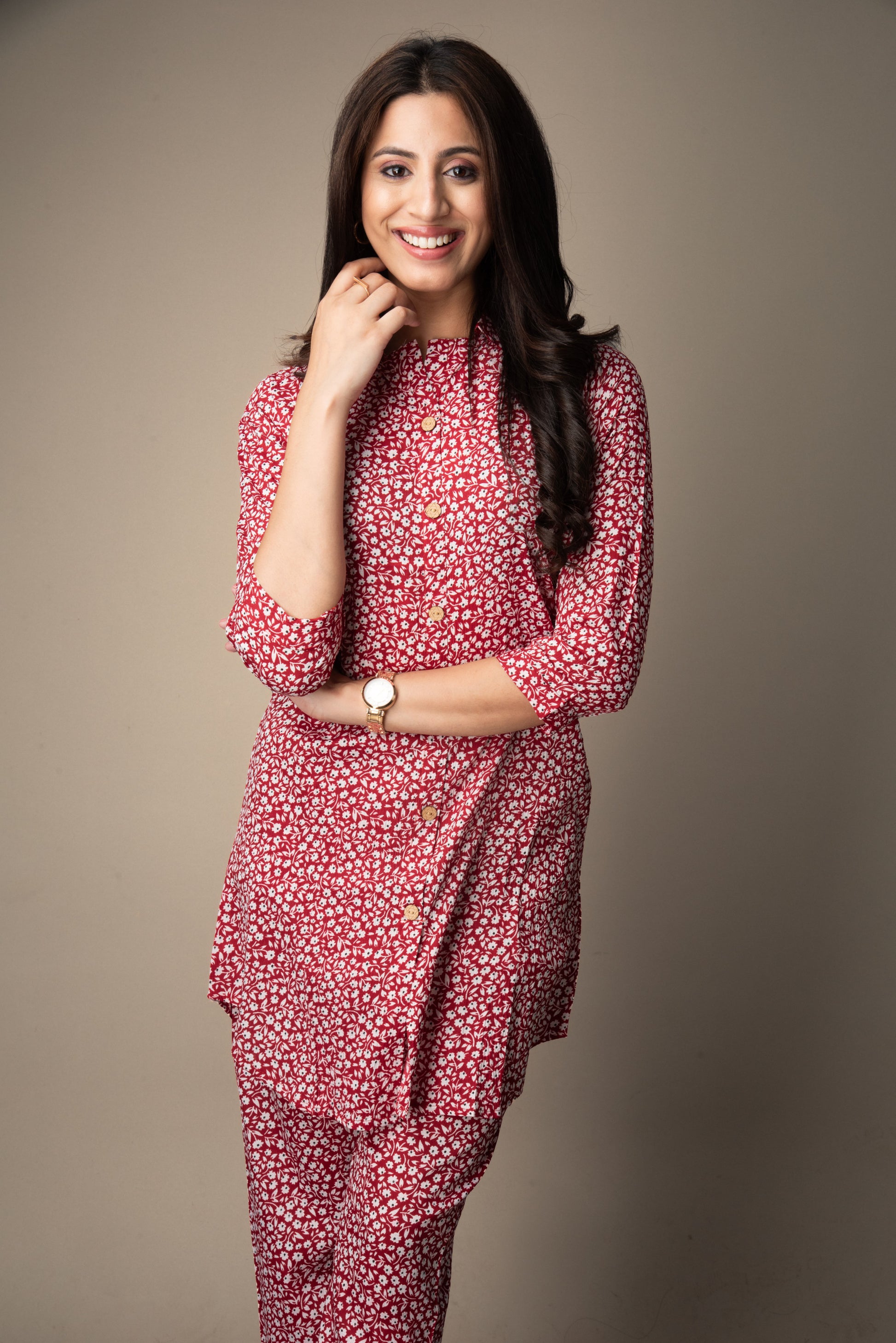 Woman wearing a red floral outfit against a plain background